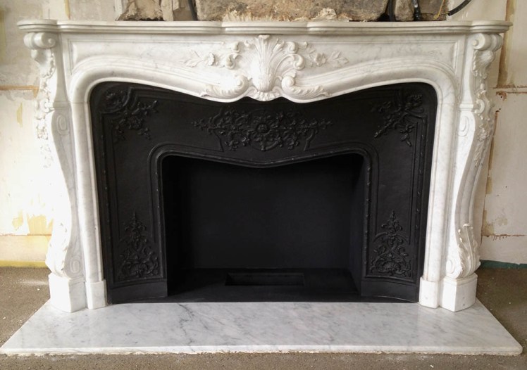 Une belle cheminée de style Louis XV en marbre avec intérieur en fonte. Le foyer est prêt à accueillir un brûleur à l'éthanol. 