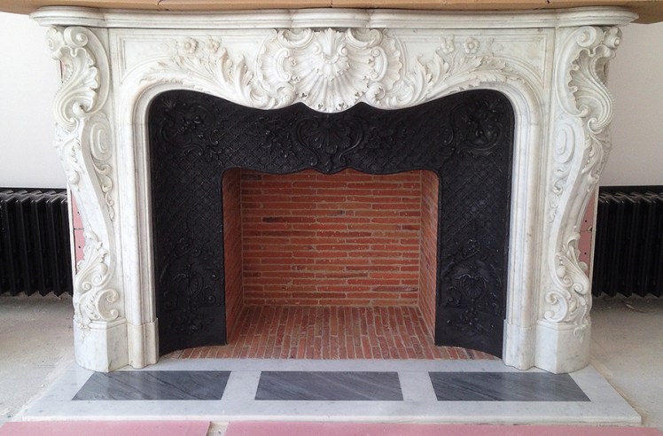 L'installation d'une exceptionnelle cheminée ancienne de style Louis XV en marbre de Carrare à Paris.